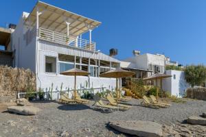 a group of chairs and umbrellas in front of a building at VistaMare2 Double room-sea view in Koutsourás +28 photos