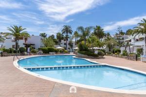 a swimming pool at a resort with palm trees at Mediterranean Way - Punta Prima in La Pineda