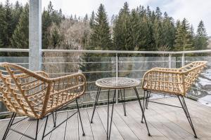 two chairs and a table on a balcony with trees at Jasmínový Ráj in Vítkovice
