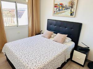 a bedroom with a bed with a blue headboard and a window at BALCON de AMADORES con vista al océano in Amadores +22 photos