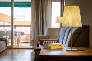 a living room with a couch and a lamp on a table at AT139 Els Pins, 1ra línea de la playa, piscina, airco, in Torredembarra