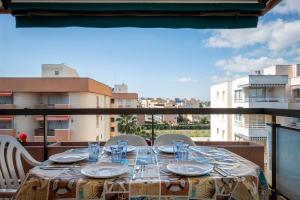 a table with plates and glasses on a balcony at AT139 Els Pins, 1ra línea de la playa, piscina, airco, in Torredembarra