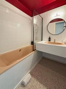 une salle de bain avec une baignoire, un lavabo et un miroir dans l'établissement Vue mer, à La Rochelle 10 autres photos