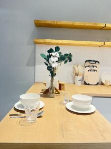 a table with plates and bowls and a vase of flowers at Просторная евродвушка люкс на Левом берегу Астаны in Astana