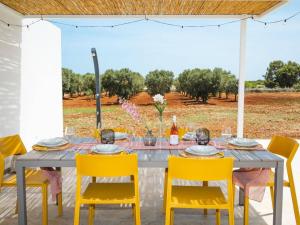 een grijze tafel met gele stoelen en een tafel met wijnglazen bij Villa Donnosanto a 5 Minuti Da Spiaggia. Ostuni 10 in Carovigno