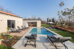 a swimming pool with lounge chairs next to a house at Villa Harmony for 8 people in Central Istria with 50 m2 private pool and sea view in Pinezići