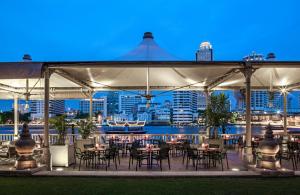 a group of tables and chairs under a white tent at The Peninsula Bangkok in Bangkok