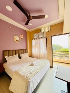 a bedroom with a large bed with a ceiling fan at Vrindas Home Stay in Maheshwar