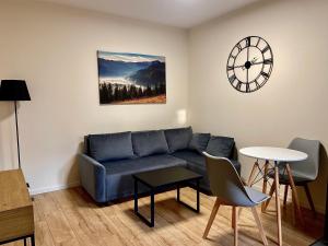 a living room with a couch and a clock on the wall at Sanriver Apartamenty in Sanok