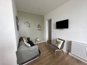 ein Wohnzimmer mit einem Sofa und einem Fernseher an der Wand in der Unterkunft Gite La Glycine, Moderne Tres Propre 3 Lits in Soultz-Haut-Rhin