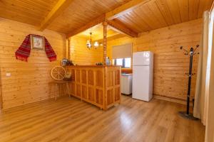 a kitchen with wooden walls and a refrigerator in a room at Cabanele FloriCrin - Cabana Mare in Mărişel