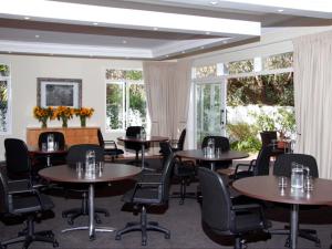 Un comedor con mesas y sillas y ventanas. en Melrose Place Boutique Hotel, en Johannesburgo