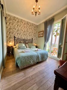 a bedroom with a bed and a chandelier at Hotel Le Ponteil in Antibes