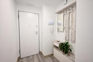 a white hallway with a door and a plant at El sonido del mar in Puerto de Sagunto