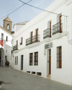 ein weißes Gebäude mit Balkon auf einer Straße in der Unterkunft Apartamentos Reysan in Vejer de la Frontera