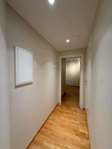 an empty hallway with a white wall and wooden floors at PP1b-Central-Cosy studio flat Suits globetrotters in Oslo