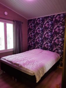 a bedroom with a bed with a purple wall at Lomahuvila Metso in Siikainen
