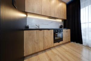 a kitchen with wooden cabinets and a stove at Urban Chic - Sokolska 30 Towers -Studio Apartment - S74 in Katowice