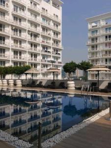 ラクナウにあるDLF Stay innの水のプールの横に傘を持つ建物