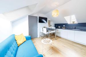 salon z niebieską kanapą i kuchnią w obiekcie L'OPAL Wifi Télétravail Centre-ville w mieście Angers