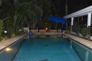 una piscina por la noche con una sombrilla azul en Sanuk bungalows, en Rawai Beach