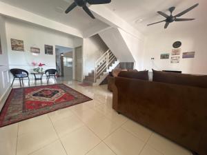 a living room with a couch and a table with chairs at Azkin Private Pool Rantau Panjang in Rantau Panjang