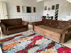 a living room with two couches and a rug at Azkin Private Pool Rantau Panjang in Rantau Panjang