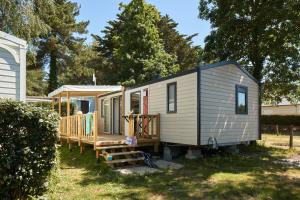 a tiny house in a yard with a porch at Camping Au Soir D'été in Mesquer