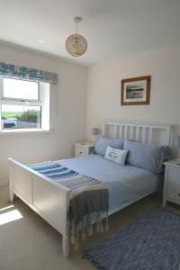 a white bedroom with a bed and a window at The Bamburgh Bolthole in Bamburgh