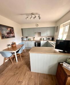 a kitchen with white cabinets and a wooden table and a dining room at The Bamburgh Bolthole in Bamburgh