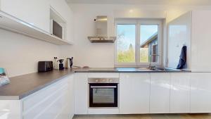 a kitchen with white cabinets and a sink and a window at Le Chalet avec Piscine - Obernai in Obernai