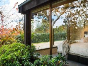 a room with a bed and a large glass window at Italian Hill Garden Villa in Daylesford