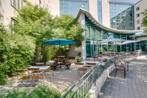 un patio al aire libre con mesas, sillas y sombrillas en Hotell Björken, en Umeå