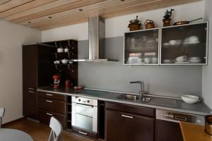 a kitchen with brown cabinets and a sink at Rožių namas ant jūros kranto in Karklė