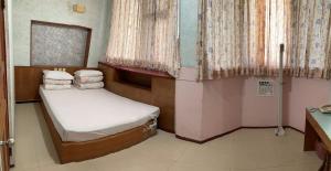 a small bedroom with a bed and curtains at New Swiss Hotel 新瑞士大旅店 in P'ing-yen-shan