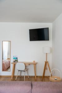 a living room with a table and a tv on a wall at The Garden in Pulsano