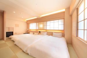 a large white bed in a room with windows at Richmond Hotel Kagoshima Kinseicho in Kagoshima