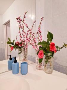 Trois vases avec des fleurs sur un comptoir dans une salle de bains dans l'établissement Gite Mont Saint Michel Chez Pépé Lucien, à La Gohannière