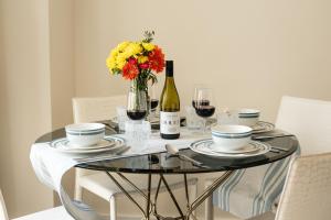 a table with a vase of flowers and a bottle of wine at Marylebone Apartments by Sleepy Lodge London in London