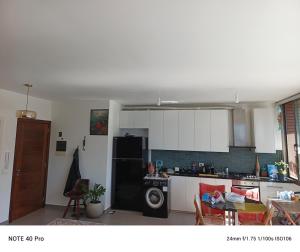 a kitchen with white cabinets and a black refrigerator at Cozy Quiet escape from the City in Fatqā