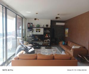 a living room with a couch and a large window at Cozy Quiet escape from the City in Fatqā