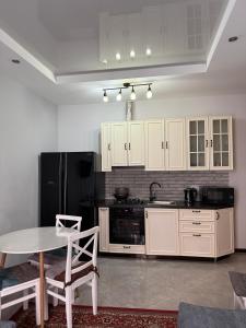a kitchen with a table and a black refrigerator at Cozy Apartment In Ortacahala in Tbilisi City