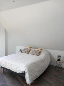 a white bedroom with a white bed with pillows at le lubermiga in Wimille