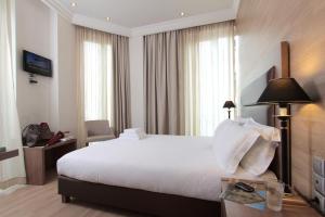 Una habitación de hotel con una cama blanca y una mesa. en Athens Lotus Hotel, en Atenas