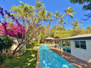 una piscina con palme e una casa di Villa 66 a L'Ermitage-Les-Bains