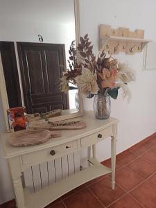 a table with a vase of flowers and a mirror at Casa Rural Gafas in El Toboso +65 photos