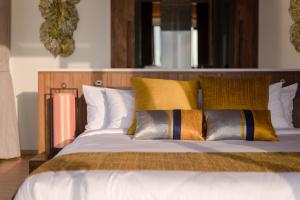 a bed with yellow and grey pillows on it at Saai Resort in Bang Saphan Noi