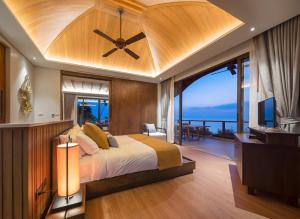 a bedroom with a large bed with a ceiling fan at Saai Resort in Bang Saphan Noi