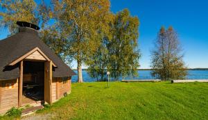 a small cabin in the grass next to a lake at Pohjanranta Cottages in Keminmaa
