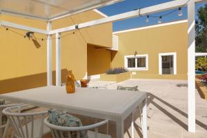 a patio with a table and chairs and a yellow house at Casa Amarela - Countryside Villa in Alcobaça